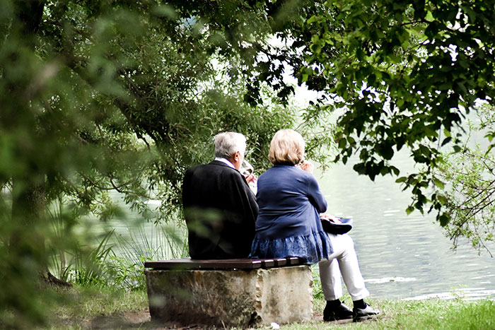 Grandparents sitting near lake and looking