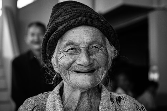 Elderly woman smiling warmly, embodying wise and funny advice from grandparents with a joyful expression.