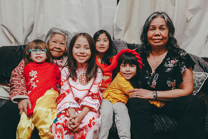 Two grandparents sitting with five smiling children, sharing moments of joy and family wisdom together.