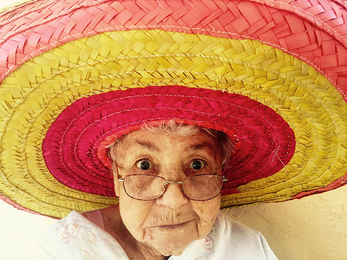 Elderly woman wearing a large colorful sombrero, embodying wise and funny advice from grandparents.