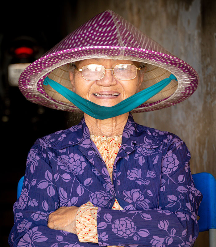 Smiling old woman wearing a hat sharing warm and funny advice from grandparents with a joyful expression.