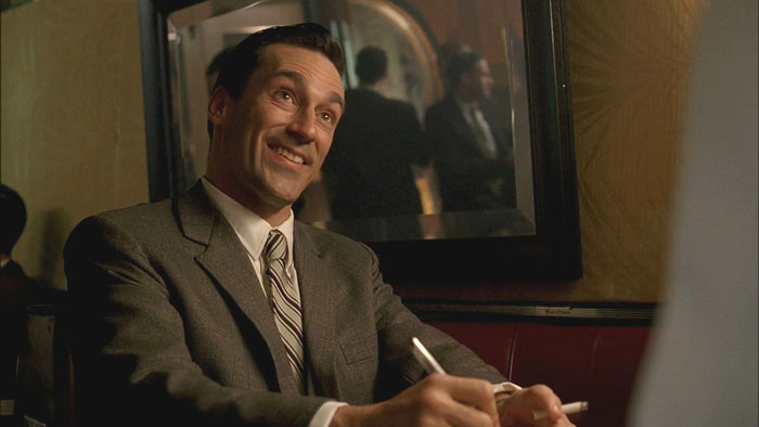 Don sitting and smiling from Mad Men Smoke Gets In Your Eyes