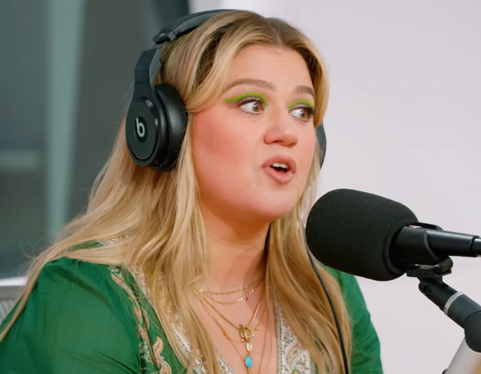Kelly Clarkson talking into a microphone with headset on 