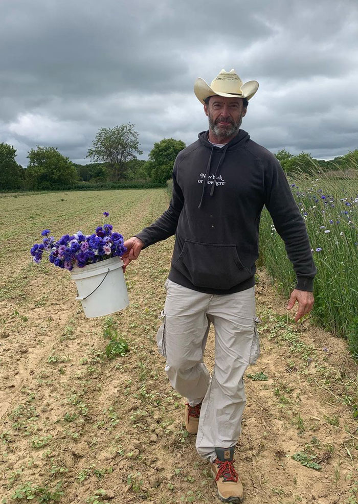 Man with a hat walking with a bucket full of flowers 