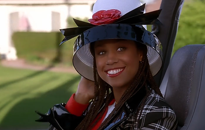 Dionne smiling wearing white and black hat with rose 