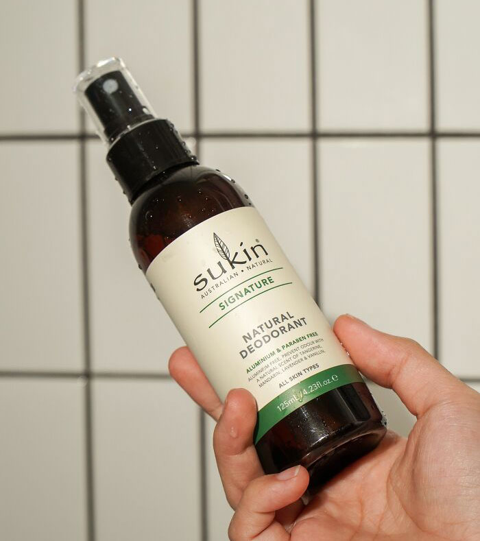 Peron holding a bottle of deodorant in shower 