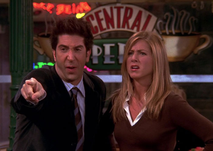 Ross pointing at someone standing next to Rachel 