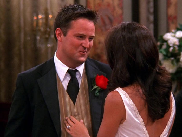 Chandler wearing suite with rose in his chest pocket 