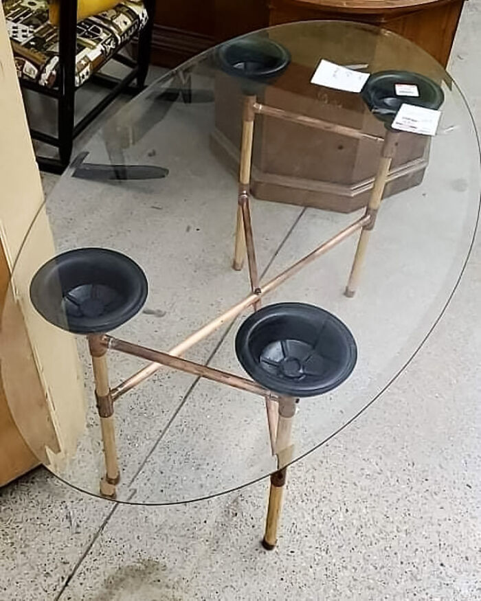 Glass coffee table with toilet plungers instead of legs 