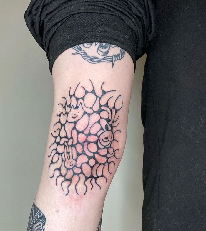 Knee tattoo featuring abstract design with faces and patterns on a person's leg.