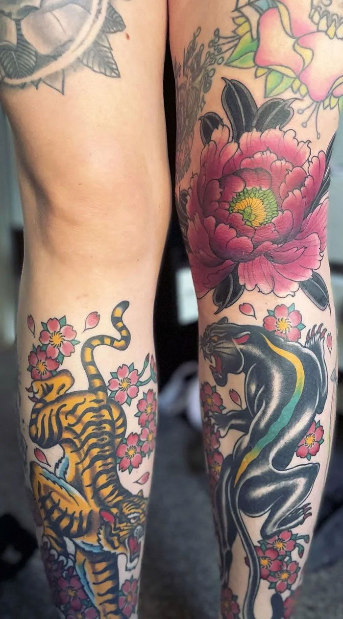 Colorful knee tattoos featuring a tiger and panther with floral accents.