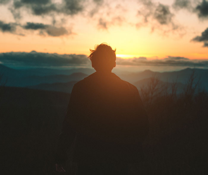 Person standing on the mountain on a sunrise 