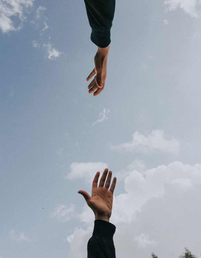 Two persons hands in the sky 