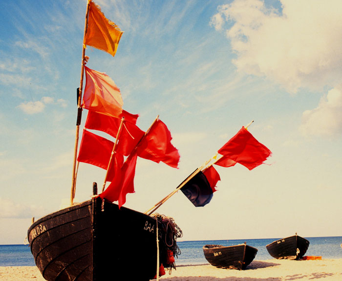 Abandoned boat with flags in an island's beach 