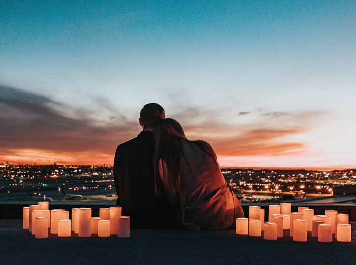 Man and woman with candles on a mountain overlooking the city 