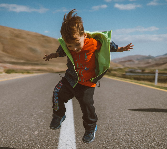 Small kid jumping in the middle of the road 