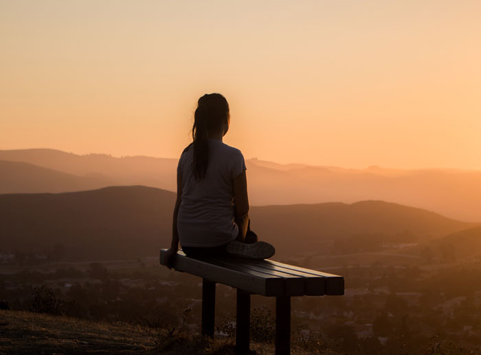 Woman sitting on a bench overlooking a city 