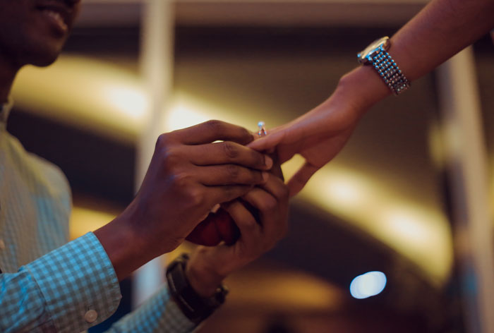 Man putting a wedding ring on woman's finger 