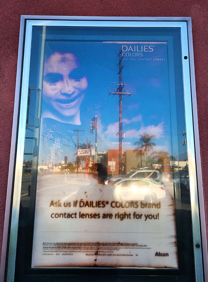 There's An Optometrist Business Near My House That Has This Giant Poster Outside Advertising Colored Contacts. It Seems To Have Aged In A "Is That A Demon?" Way