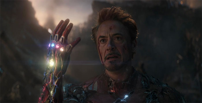 Tony Stark has a bloody face, and his right hand is glowing