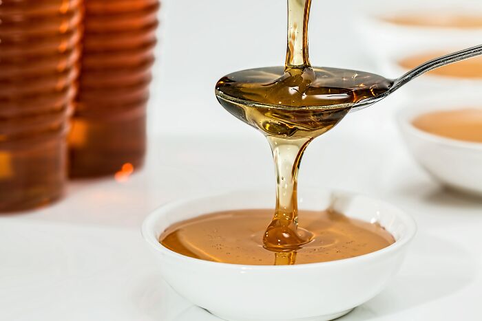 Poring Honey Through The Spoon To A Bowl