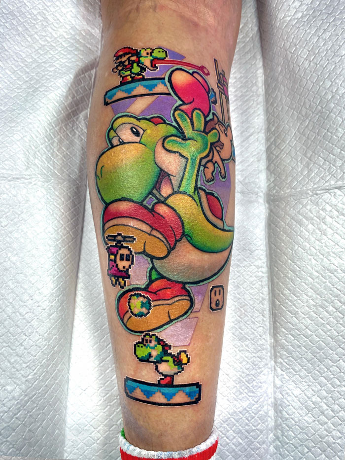 Colorful pop culture tattoo of a cartoon character with pixelated elements on a person's leg.