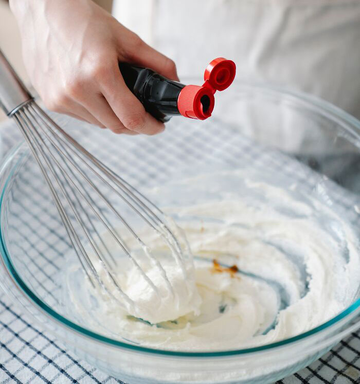 Person putting Vanilla extract in to the cream 