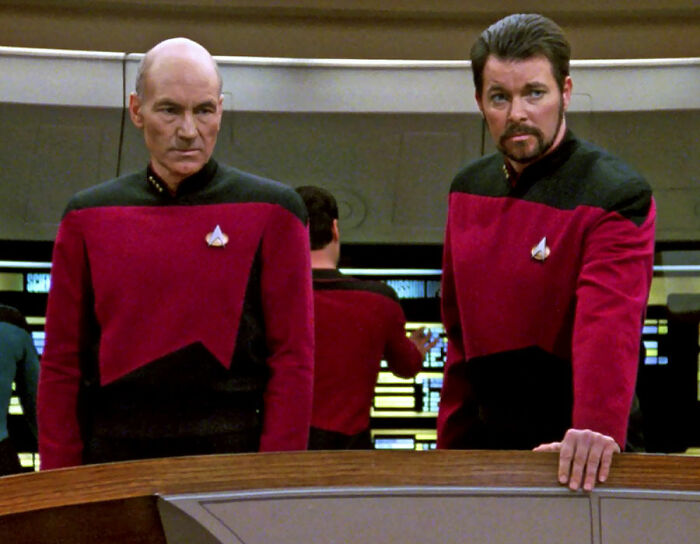 Jean-Luc Picard and William T. Riker looking over the crew