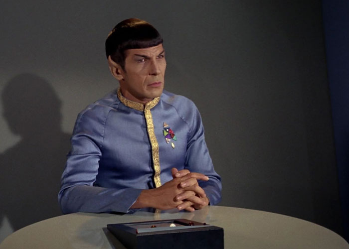 Spock sitting next to a table with hands together
