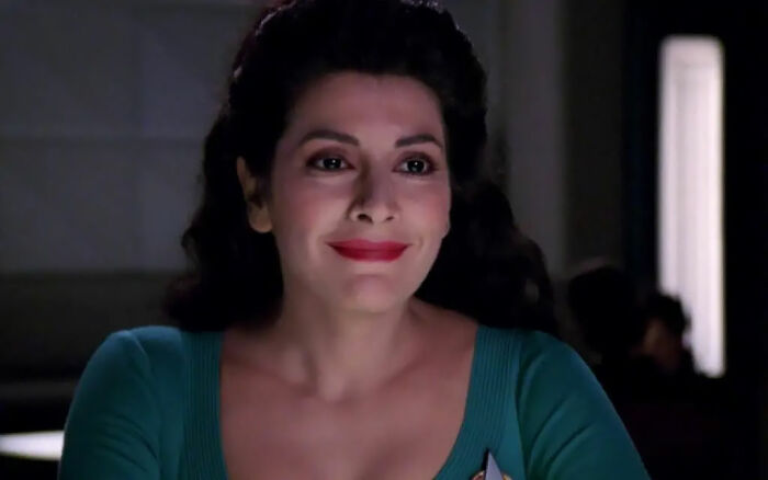 Deanna Troi smiling in a very friendly manner