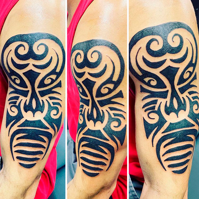 Close-up of a tribal tattoo design on an arm, featuring bold black patterns and intricate swirls.