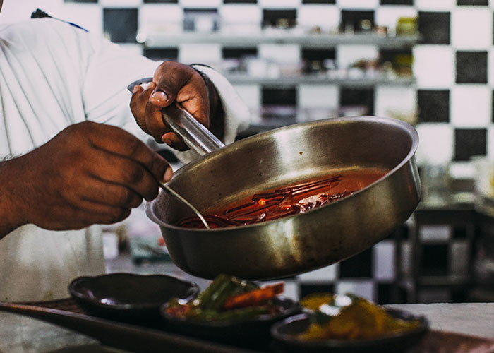 Chef preparing a sauce in a pan, showcasing one of the unique college courses related to culinary arts.