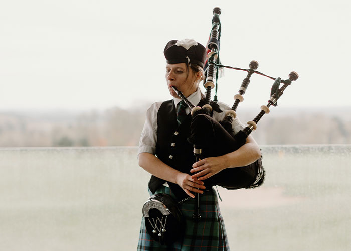 Female student in traditional Scottish attire playing bagpipes, representing unique college courses you probably never knew existed.