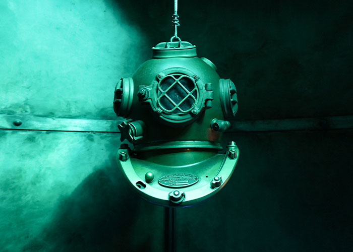 Vintage deep-sea diving helmet displayed in a museum setting, illustrating unique college courses related to marine studies.