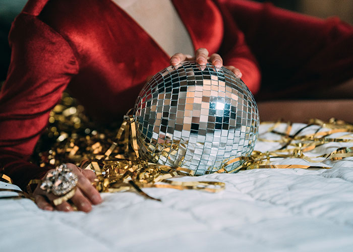 Person in red outfit holding a mirrored disco ball surrounded by gold ribbons representing unique college courses concept
