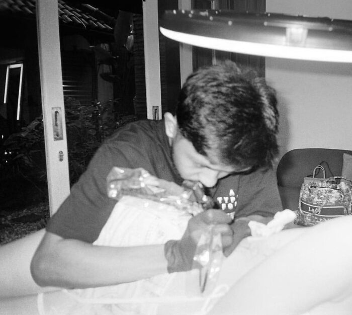 Tattoo artist concentrating on creating a geometric design on a client's arm in a relaxed studio environment. Tattoo artist concentrating on creating a geometric design on a client's arm in a relaxed studio environment.