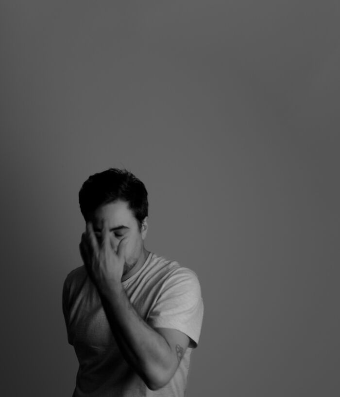 Tattoo artist in grayscale, hand over face, wearing a light shirt, showcasing individual style and expression. Tattoo artist in grayscale, hand over face, wearing a light shirt, showcasing individual style and expression.