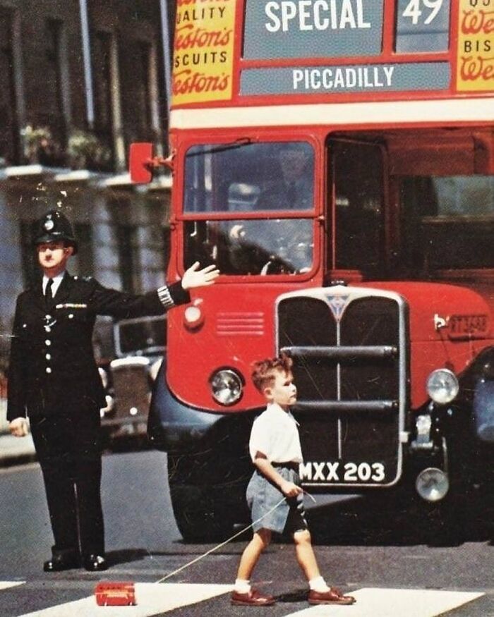 Niño cruzando la calle en Londres con un autobús de juguete. Años 60