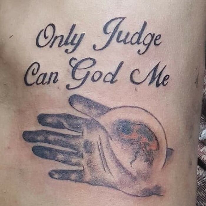 Badly drawn tattoo of hands with misspelled quote "Only Judge Can God Me".