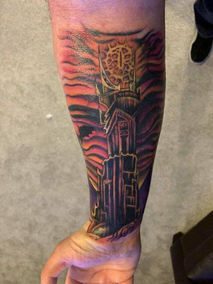 Forearm tattoo featuring the Eye of Sauron from Lord of the Rings, with a fiery design background.