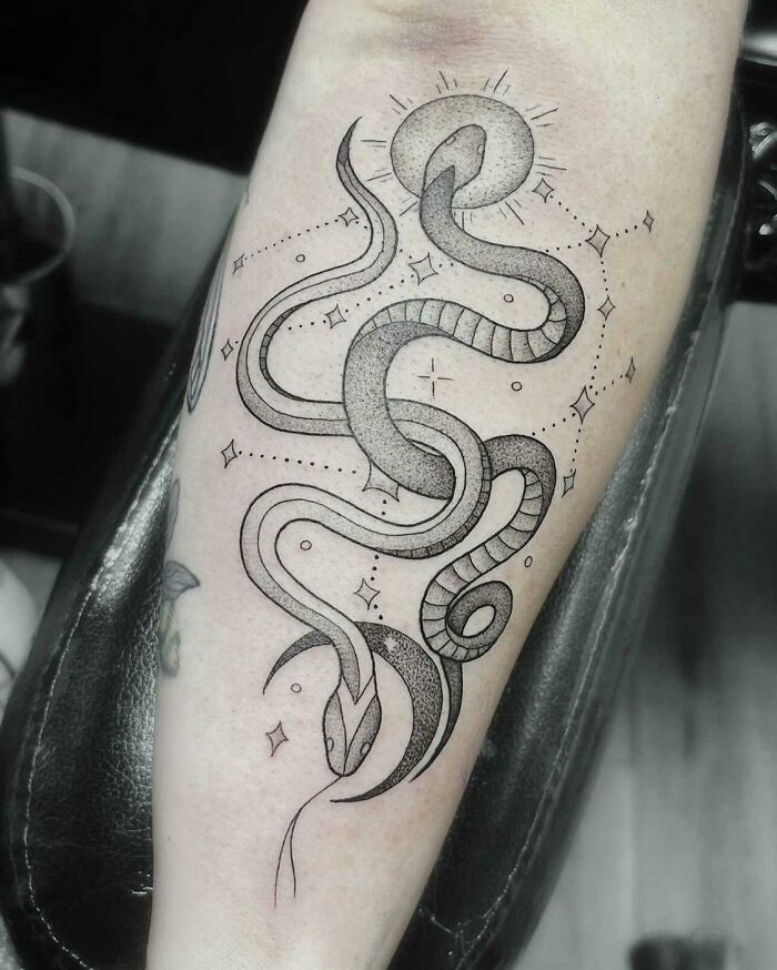 Intricate zodiac tattoo featuring a stylized snake design with celestial accents on forearm.
