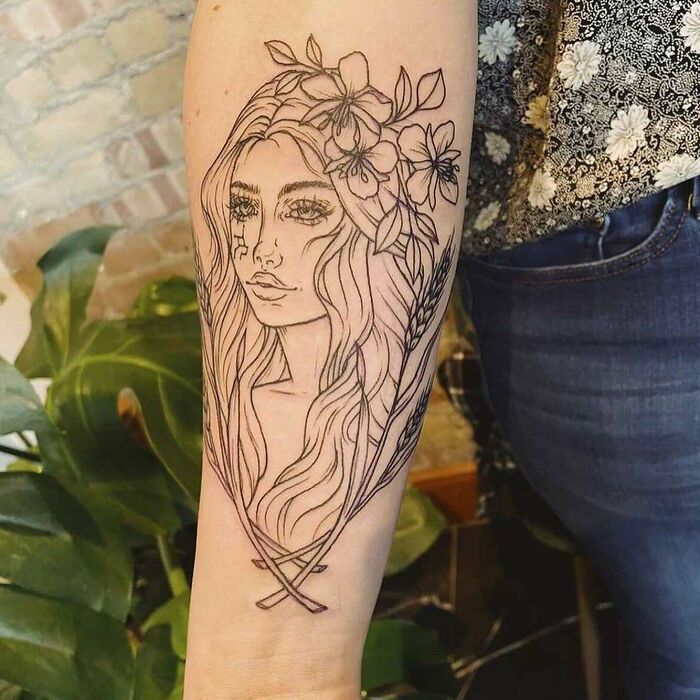 Arm tattoo featuring a woman's portrait with floral crown, representing zodiac themes.