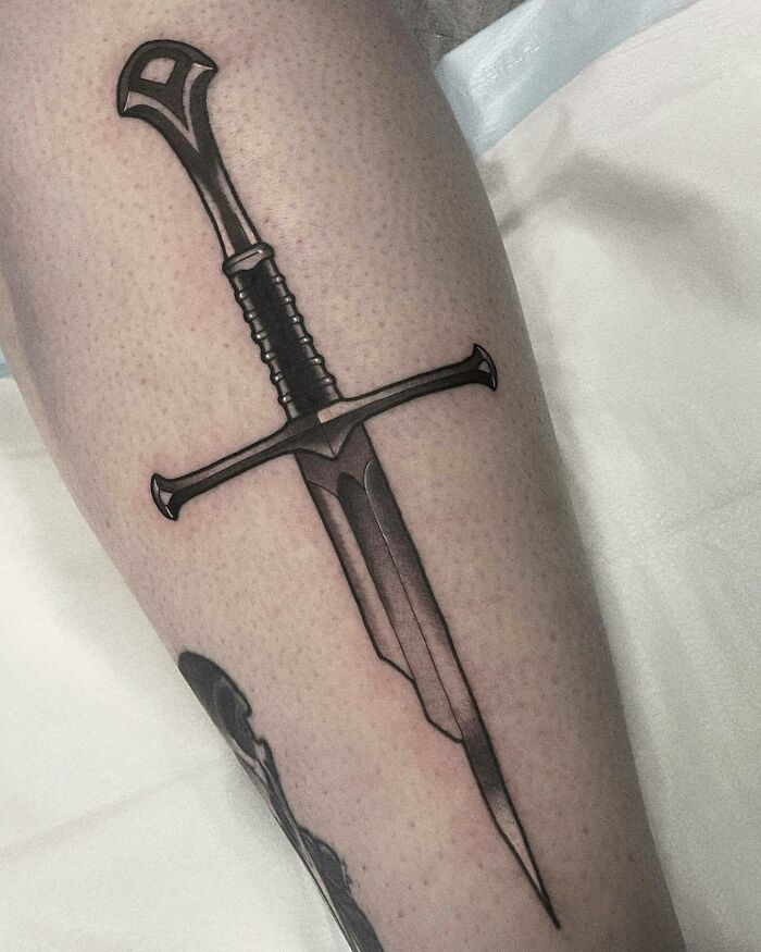 Sword tattoo inspired by Lord of the Rings, elegantly designed on a person's leg.