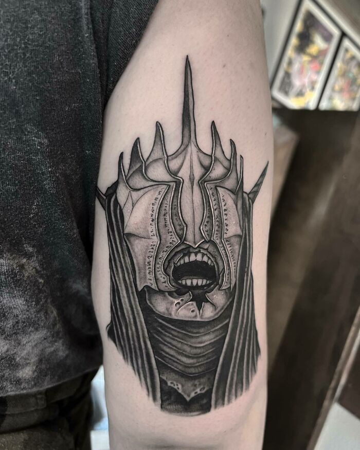 "Intricate Lord of the Rings tattoo featuring a detailed armored helmet on an upper arm."