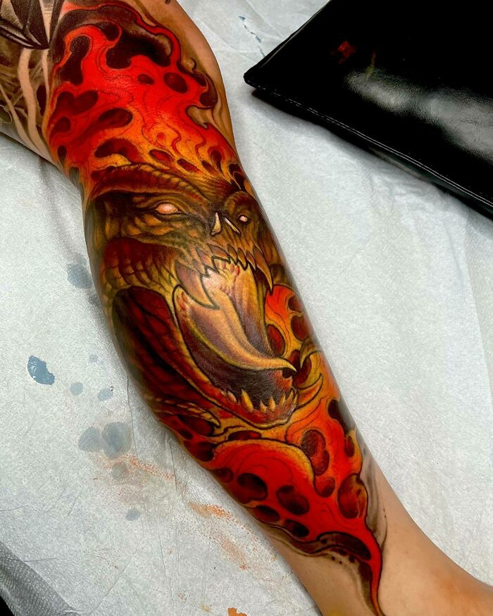 Colorful Lord of the Rings tattoo depicting a fiery creature on an arm in vivid detail.