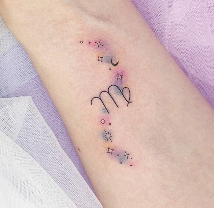 Virgo zodiac tattoo with colorful stars and moon on forearm.