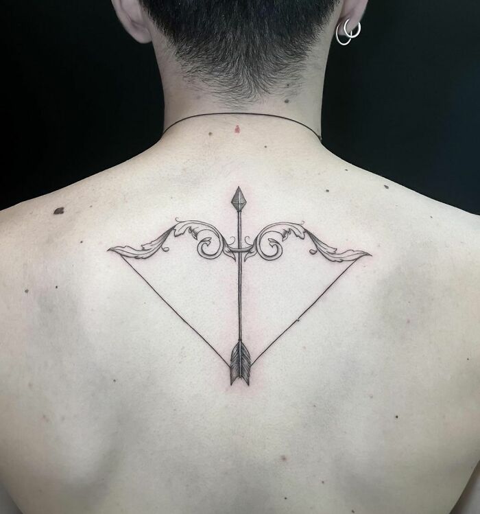 Elegant arrow zodiac tattoo on back with intricate design.