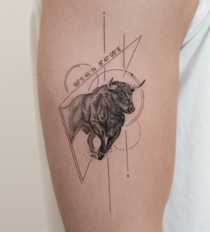 Tattoo of a bull with geometric elements, featuring zodiac design on an arm.