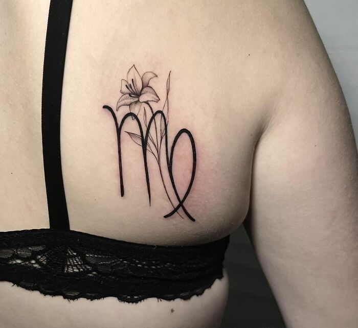 Delicate Virgo zodiac tattoo with floral design on person's upper back.