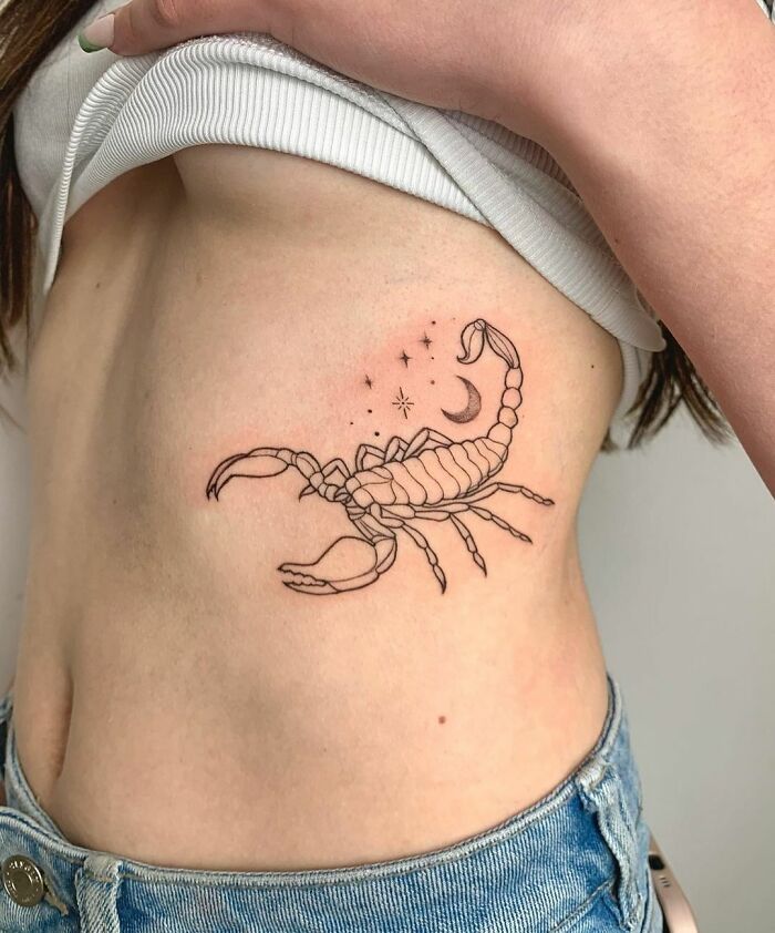 Scorpio zodiac tattoo featuring a detailed scorpion with stars and a moon on the side of a person's torso.